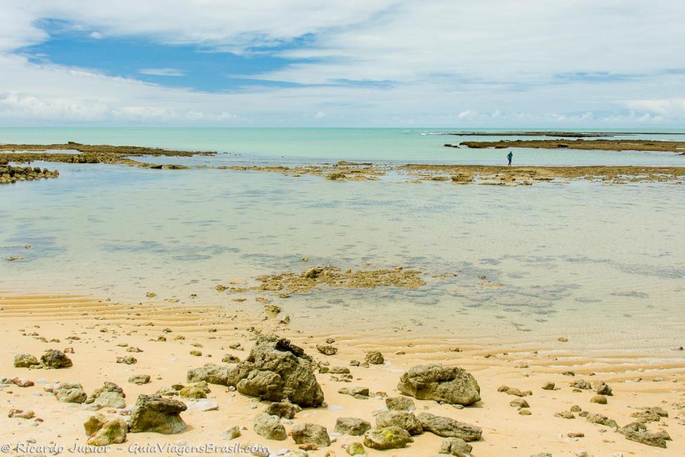 Imagem das pedras nas águas translúcidas da Praia do Espelho.